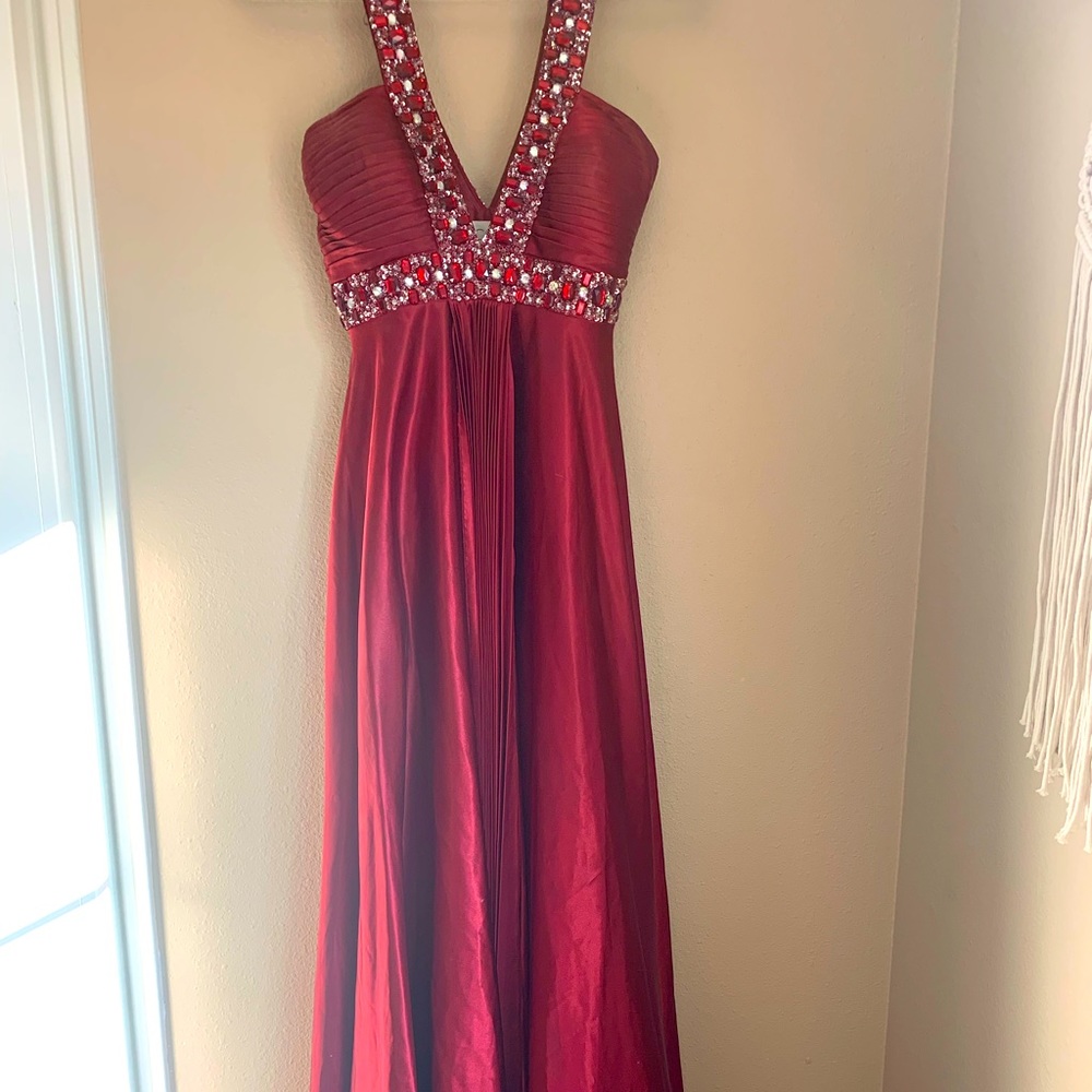 Deep red floor length gown with red and clear gems alongside V neck.